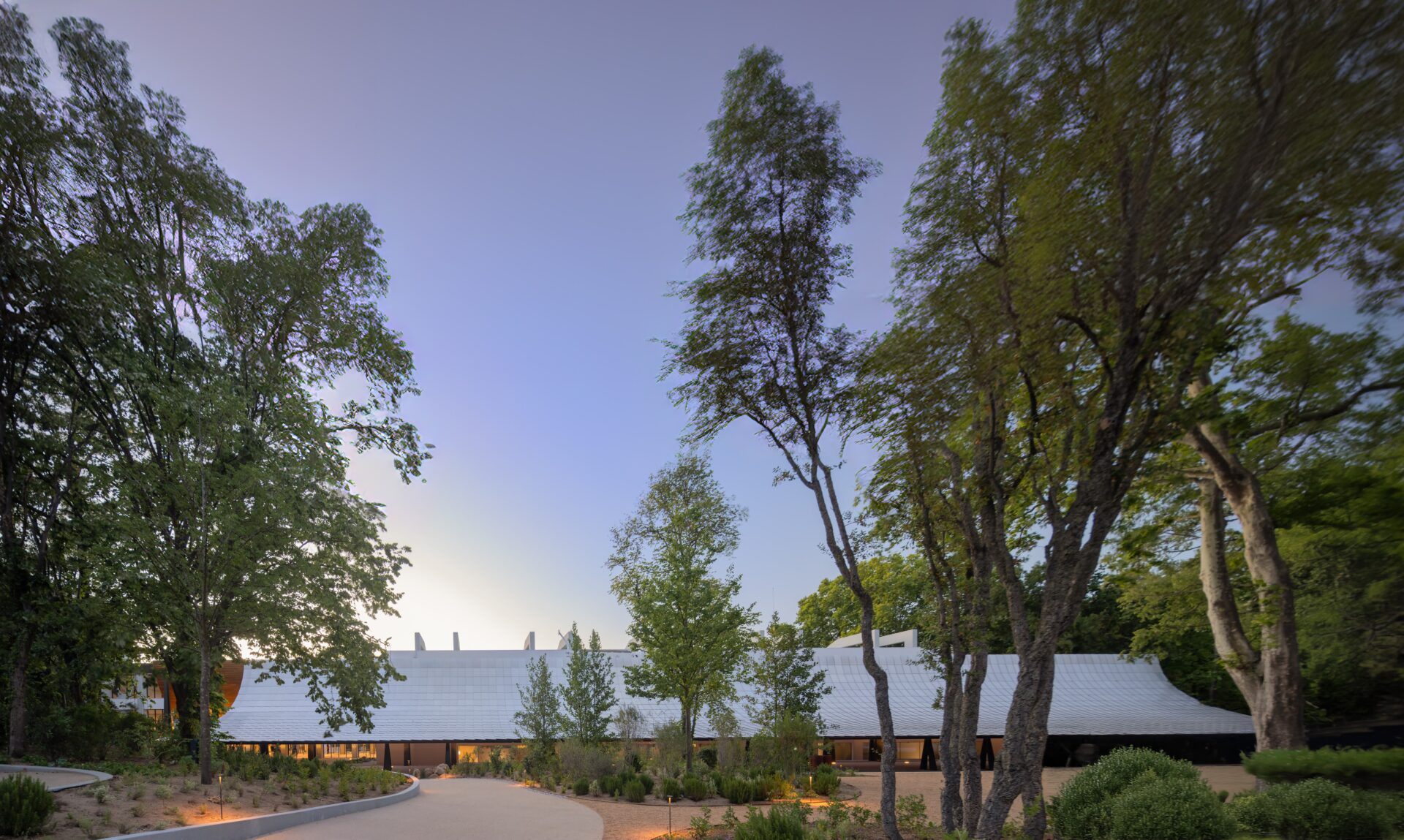 A garden surrounded by trees and the building of an art museum.