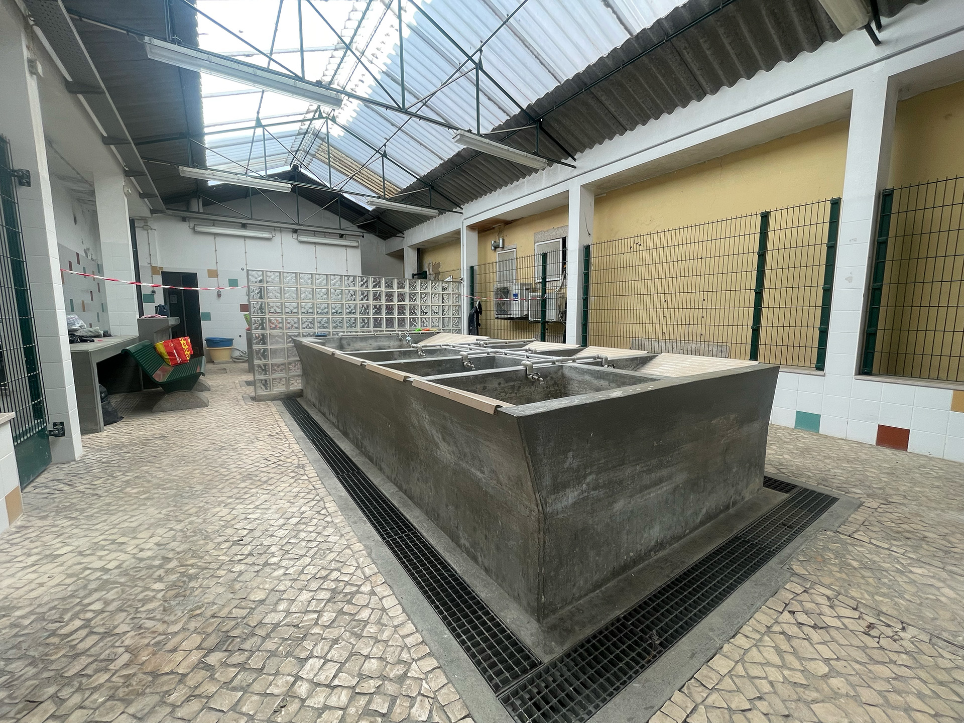 Indoor washhouse visited during research: stone washing basins lined up inside a tiled room.