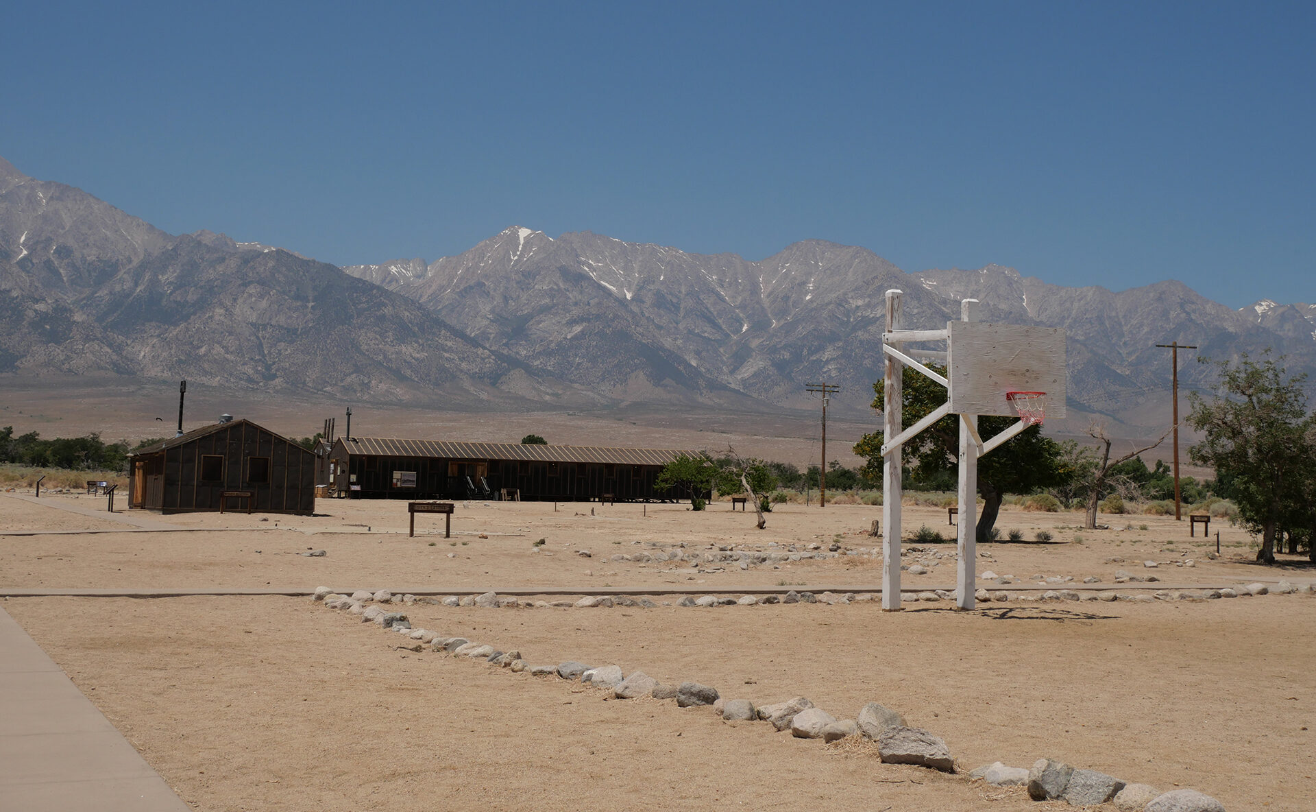 A wide expanse of sandy terrain at the Manzanar internment camp, with mountains visible in the distance.