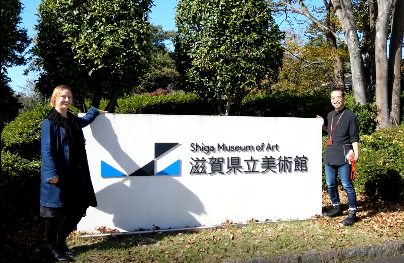 Melanie and Arai standing next to the entrance sign of the Shiga Museum of Art.