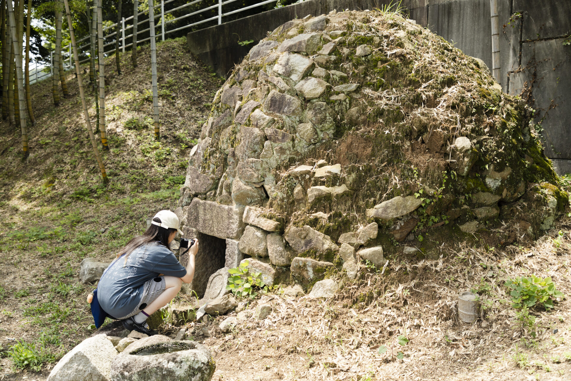 Aoyagi leaning in from outside the stone bath to film inside.
