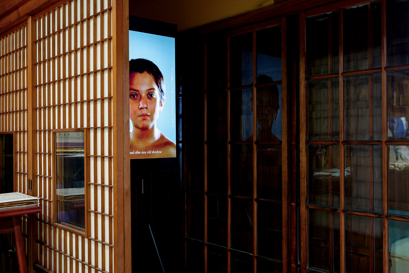 Installation view with a video monitor set up behind a shoji screen wall.